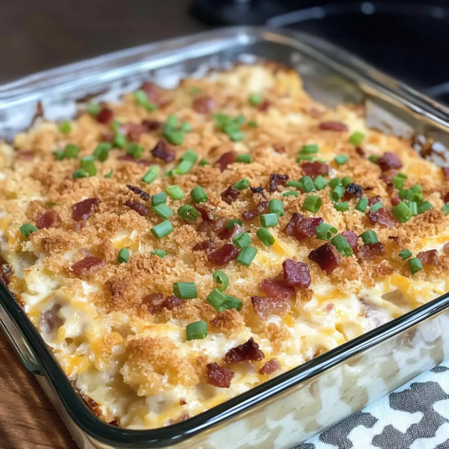 A close-up of a baked macaroni and cheese dish topped with crispy breadcrumbs, bacon bits, and chopped green onions.