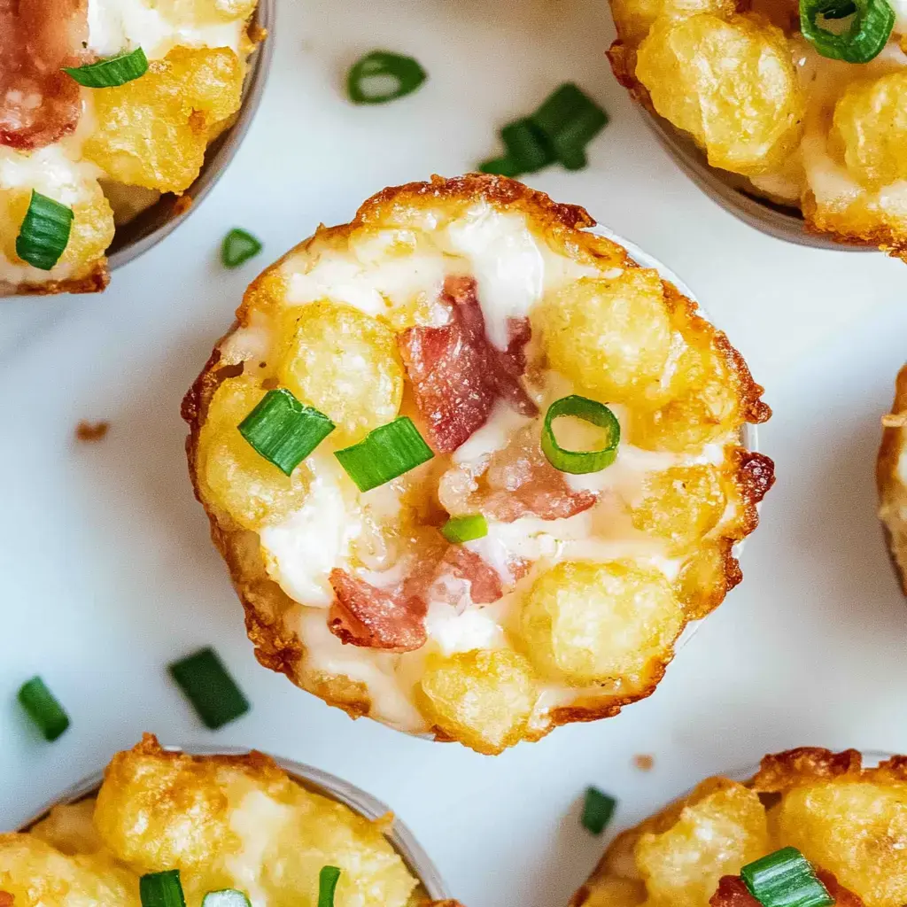 Miniature baked cups made of crispy potatoes, topped with cheese, bacon bits, and green onions, arranged on a white surface.