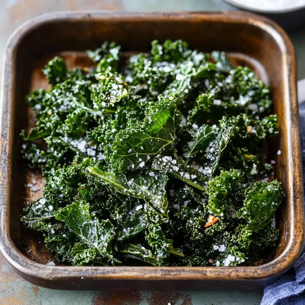 A serving of seasoned, crispy kale is presented in a wooden tray, sprinkled with coarse salt.