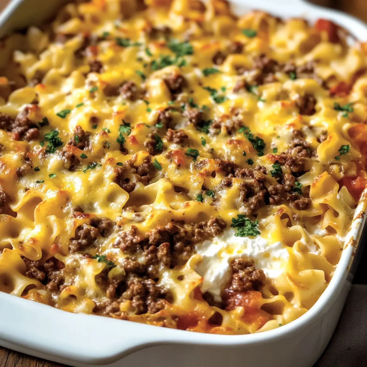 A baked dish of noodles topped with ground beef, melted cheese, and parsley.