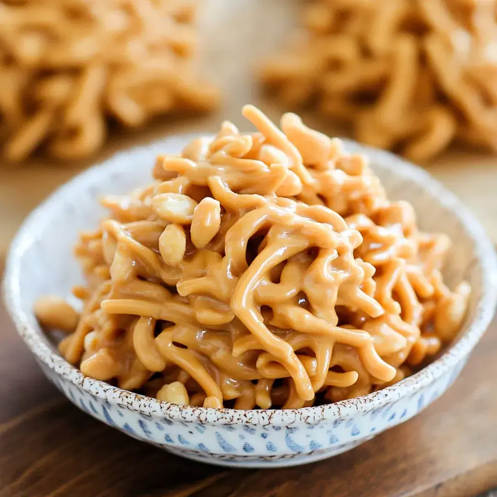 A bowl filled with a sticky, caramelized mixture of crunchy noodles and peanuts.