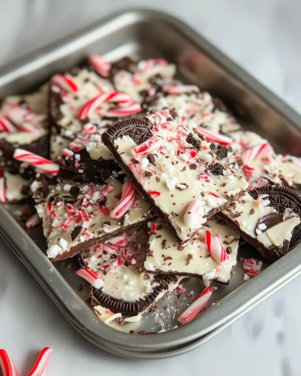 A tray of chocolate bark topped with white chocolate, crushed peppermints, and Oreo pieces.