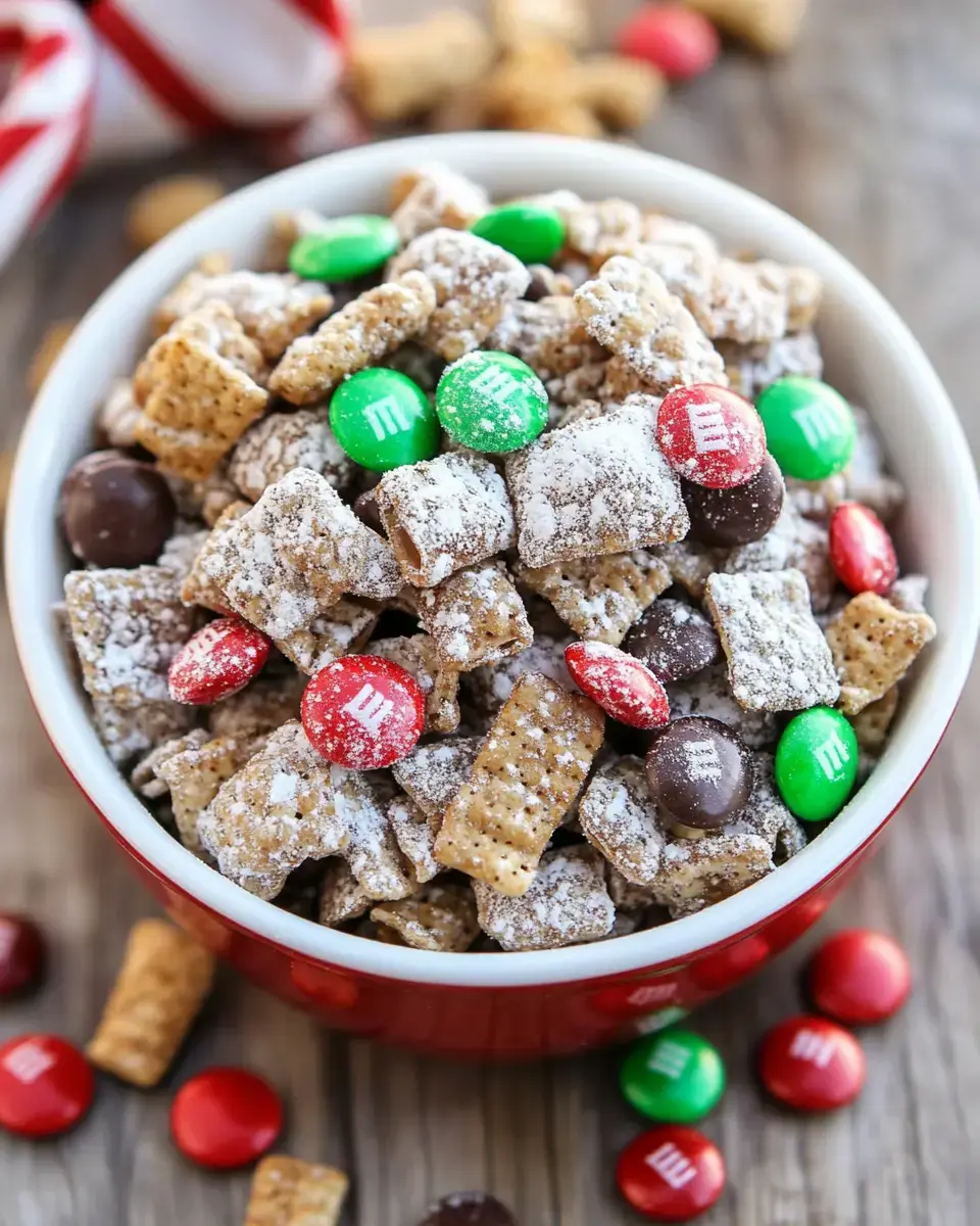 A bowl of sweet snack mix featuring cereal pieces, powdered sugar, and colorful M&M candies scattered around on a wooden surface.