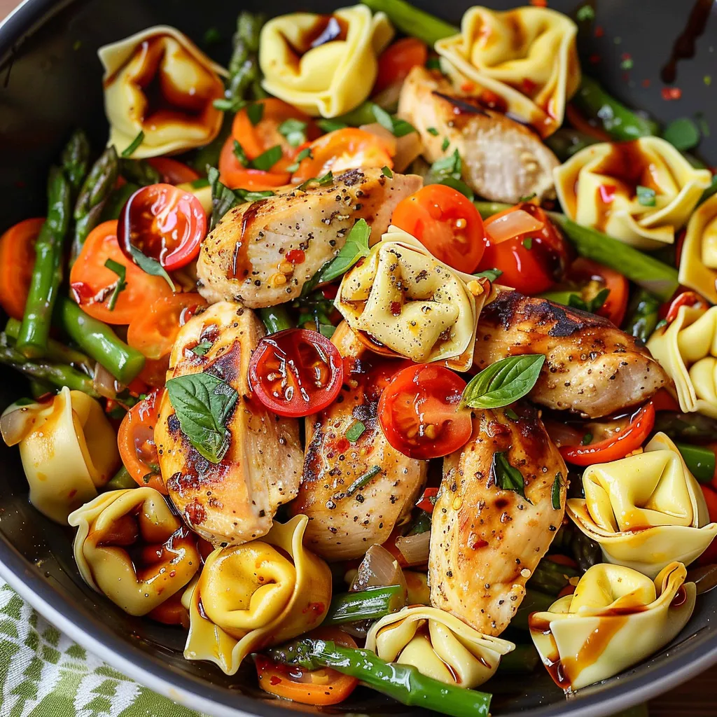 A bowl of food with chicken, tomatoes, and pasta.