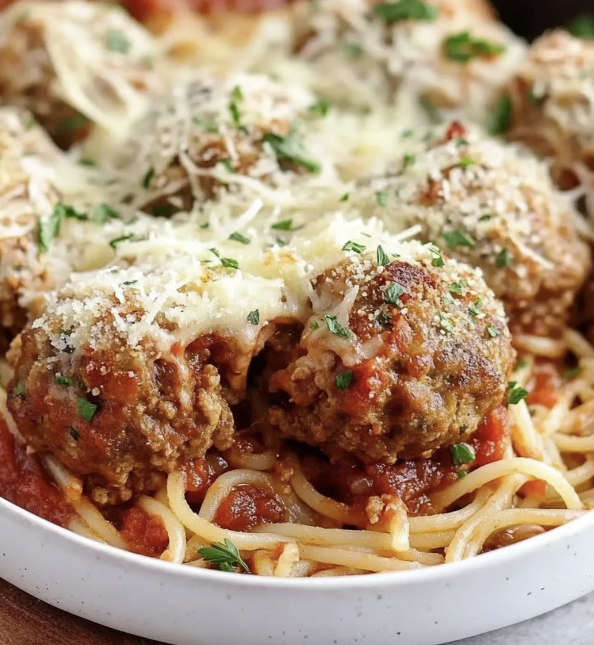 A plate of meatballs covered in cheese and tomato sauce.