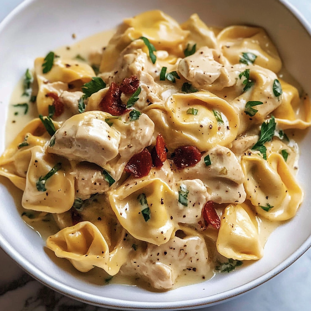 A bowl of pasta with chicken and tomatoes.