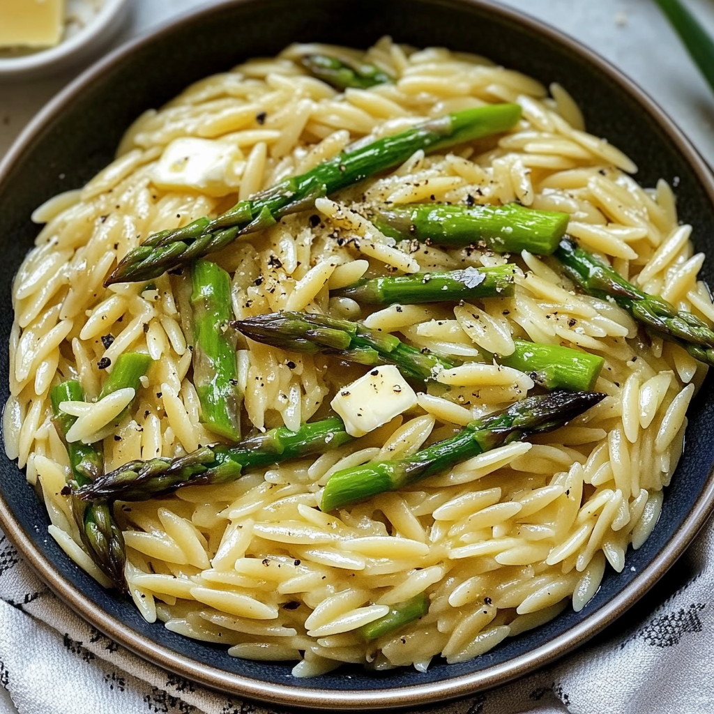A bowl of pasta with asparagus and cheese on top.