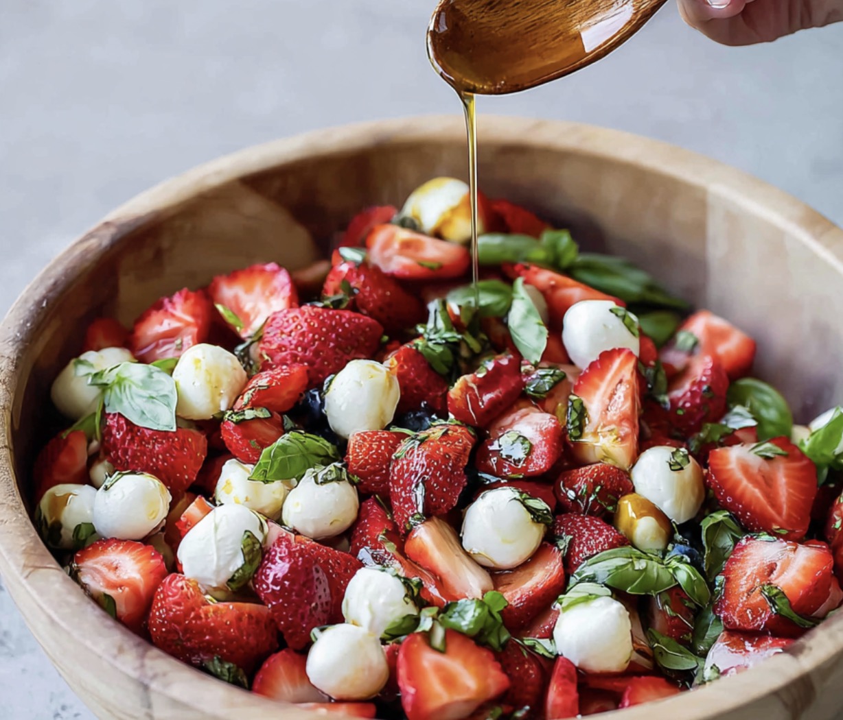 A bowl of fresh strawberries and cheese with a drizzle of olive oil.