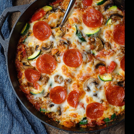 A delicious pizza pie with pepperoni, mushrooms, and zucchini, all cooked in a black skillet.