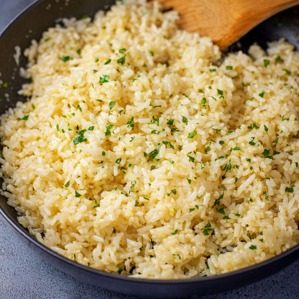 A bowl of rice with green herbs on top.