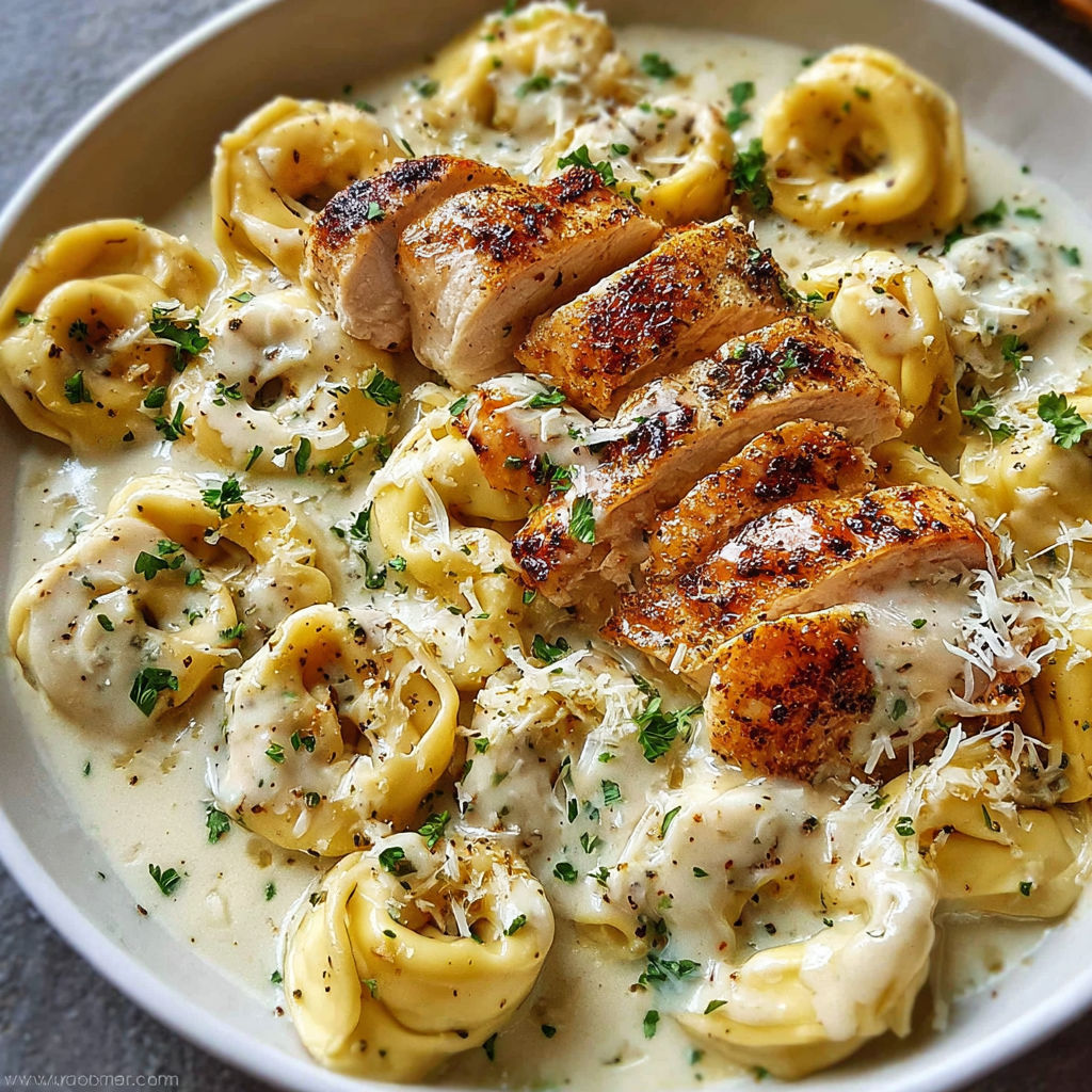 A bowl of pasta with chicken and cheese, the dish is called Asiago Tortellini Alfredo with Grilled Chicken Recipe.