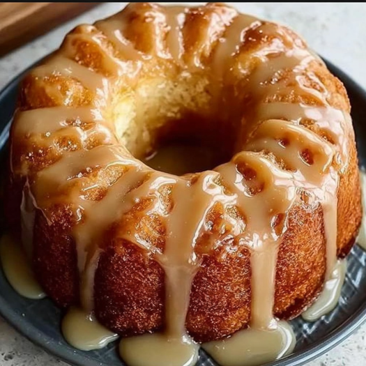 A cake with a glaze dripping down the side, sitting on a plate.