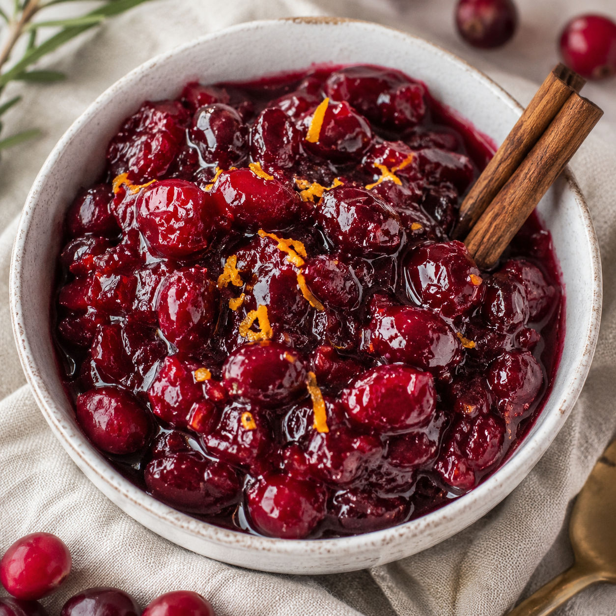 Glossy cranberry sauce with orange zest and cinnamon in a white bowl