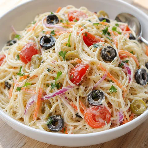 Creamy angel hair pasta salad with olives, tomatoes, carrots, and parsley
