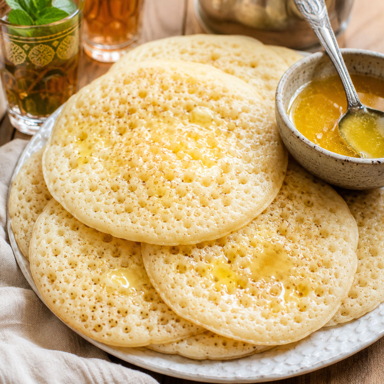 Moroccan baghrir pancakes with honey butter on a white plate