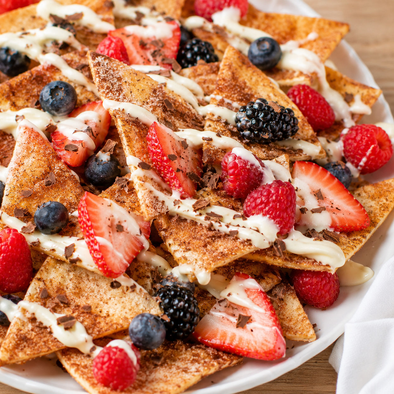 Berry dessert nachos with cinnamon chips and cream cheese drizzle