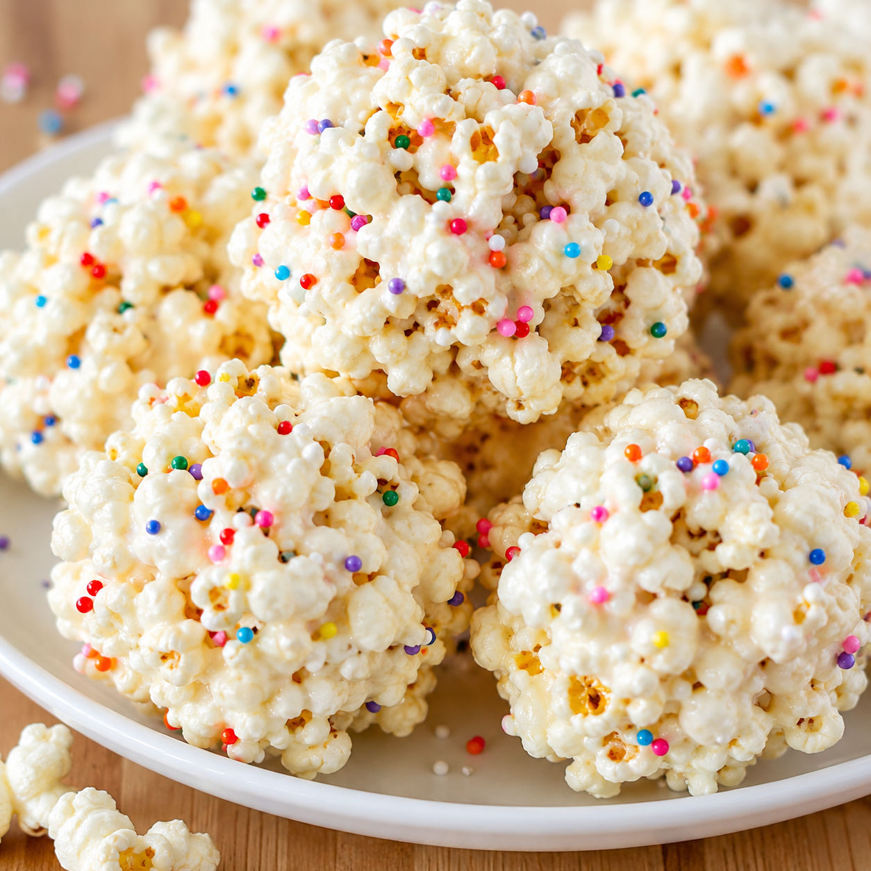 Chewy popcorn balls with sprinkles stacked on a white plate