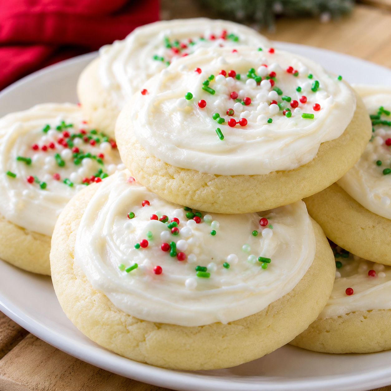 Soft frosted Christmas cookies with red and green sprinkles on a white plate