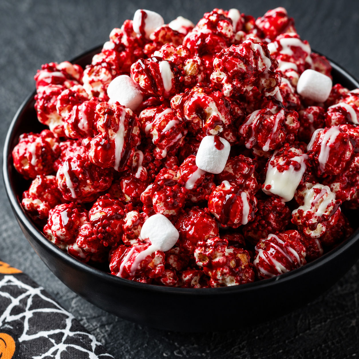 Bloody red velvet popcorn with white drizzle in a black bowl