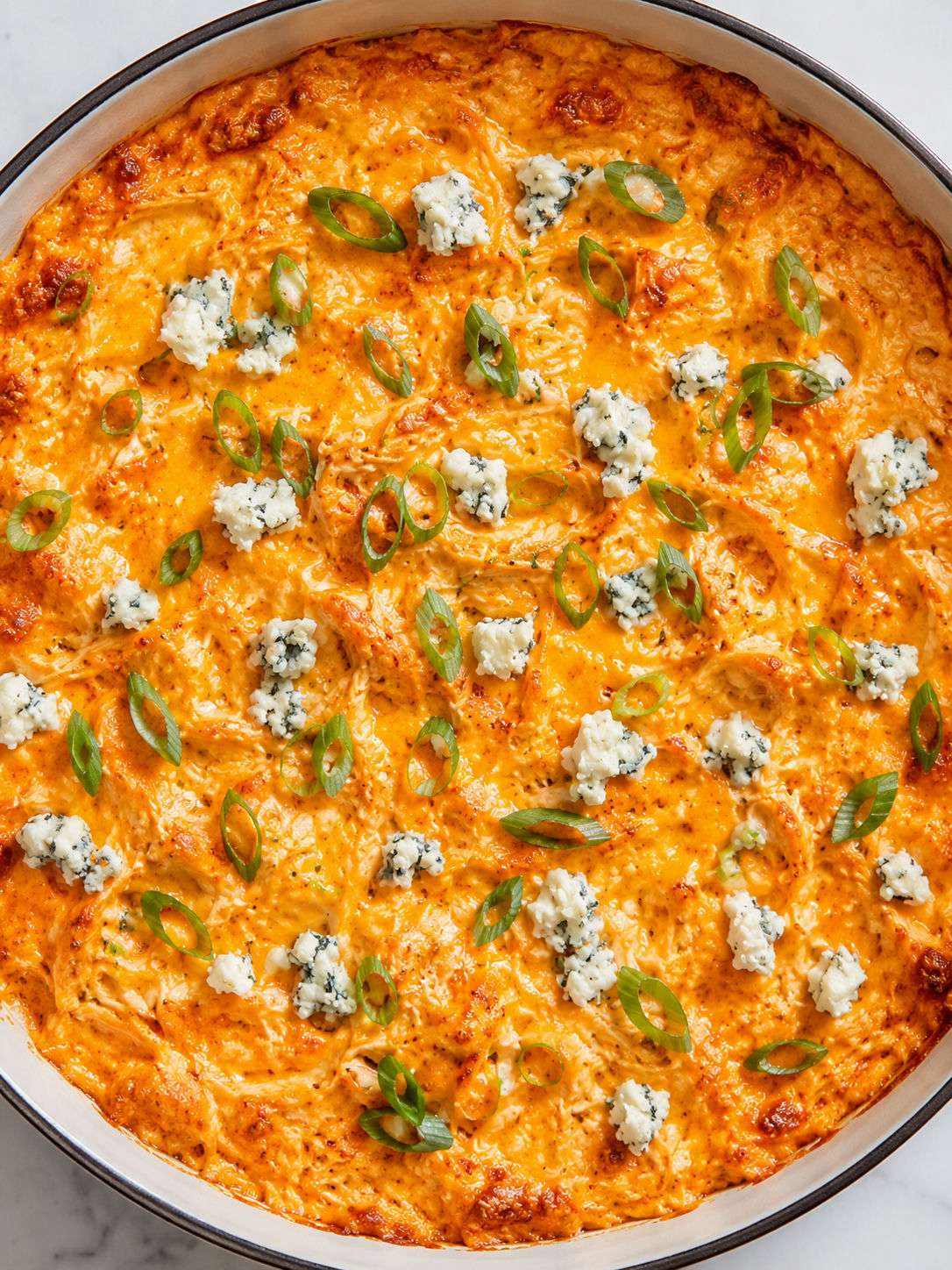 Top-down Buffalo Chicken Dip with melted cheese, scallions, and chips