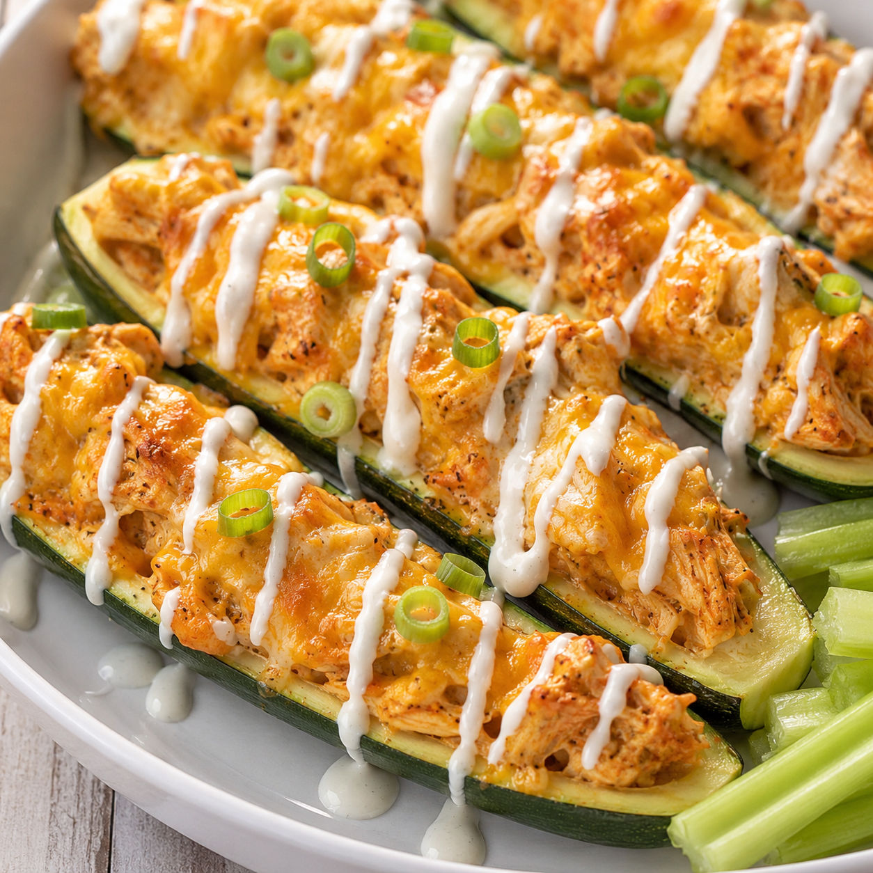 Buffalo chicken zucchini boats with melted cheese, ranch, and green onions
