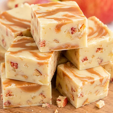 Caramel apple fudge squares with caramel swirl and dried apple on a wooden board