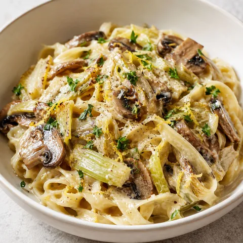 Caramelized leek and mushroom Gruyere pasta with parsley in a shallow bowl