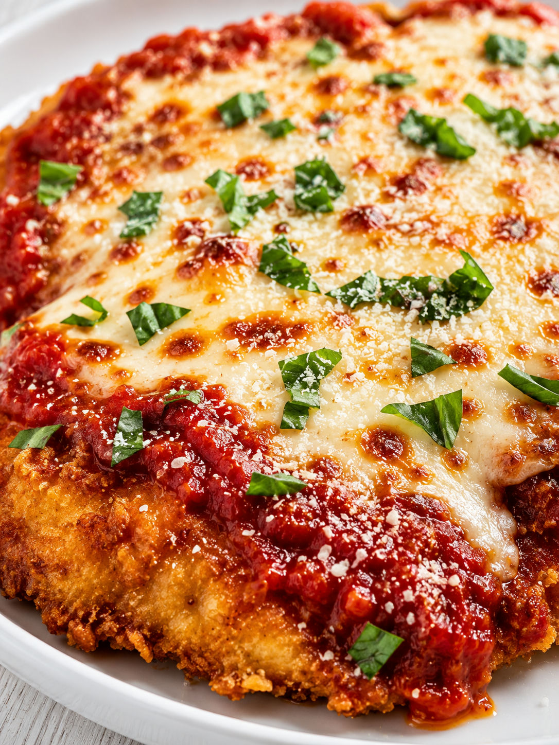 Crispy chicken Parmesan with glossy marinara, melted mozzarella, and basil