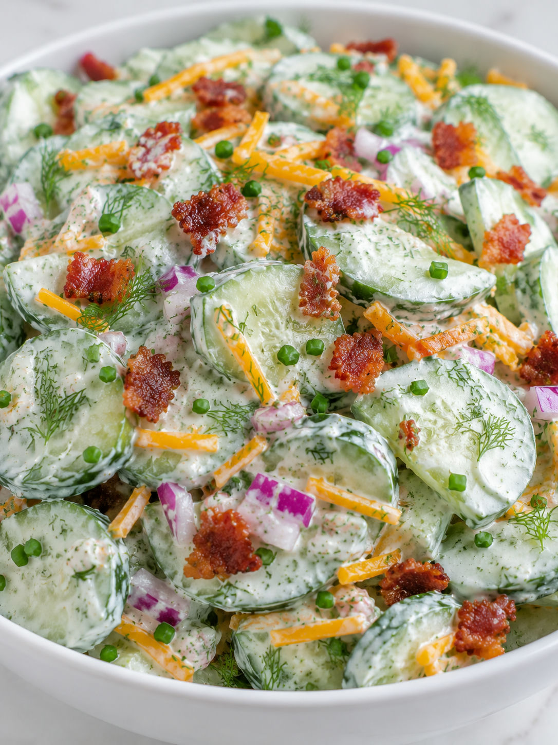 Creamy cucumber ranch salad with bacon, cheddar, red onion, and herbs