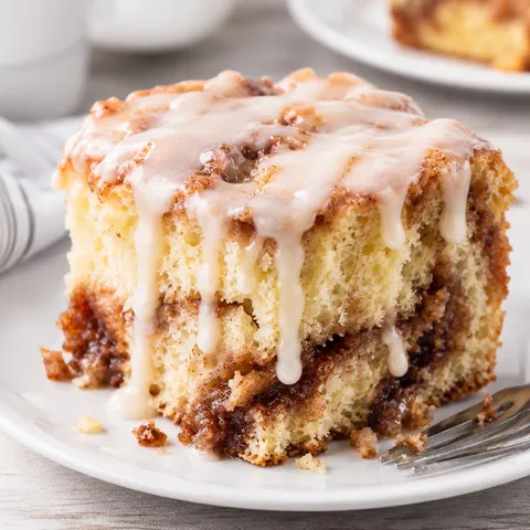 Cinnamon roll cake square with white glaze and brown cinnamon swirls