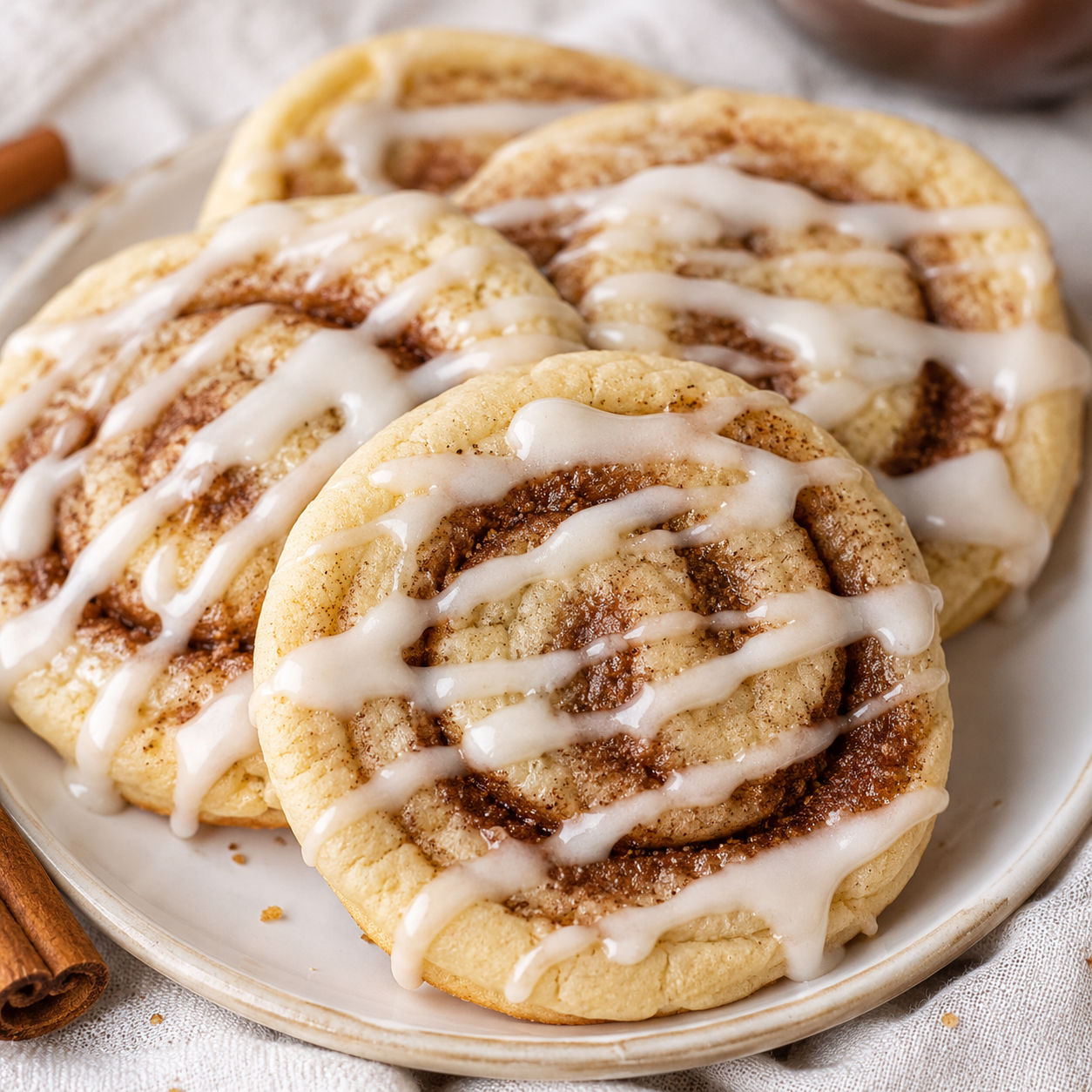 Cinnamon roll sugar cookies with cream cheese glaze on a white plate