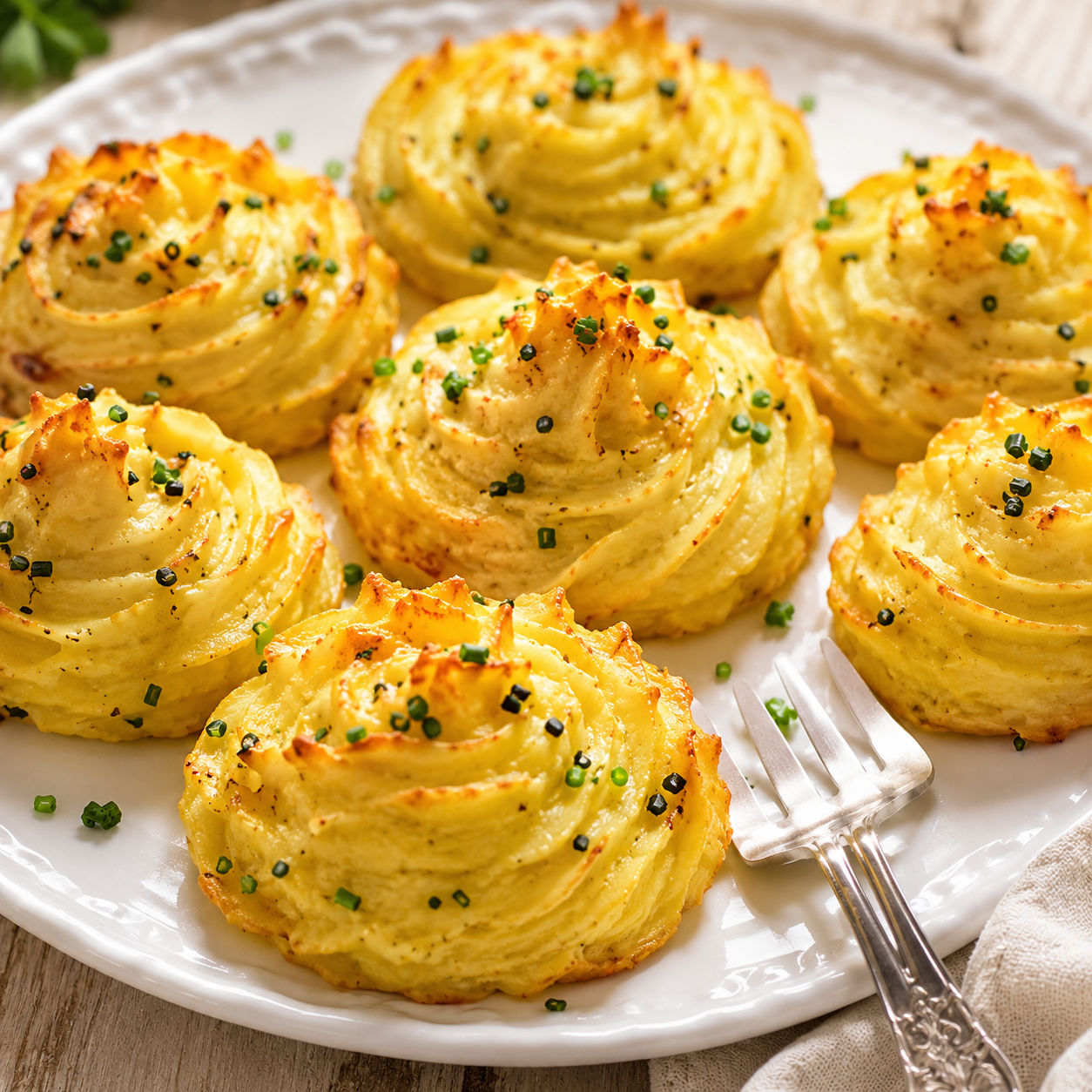 Golden Duchess Potatoes with chives on a white platter