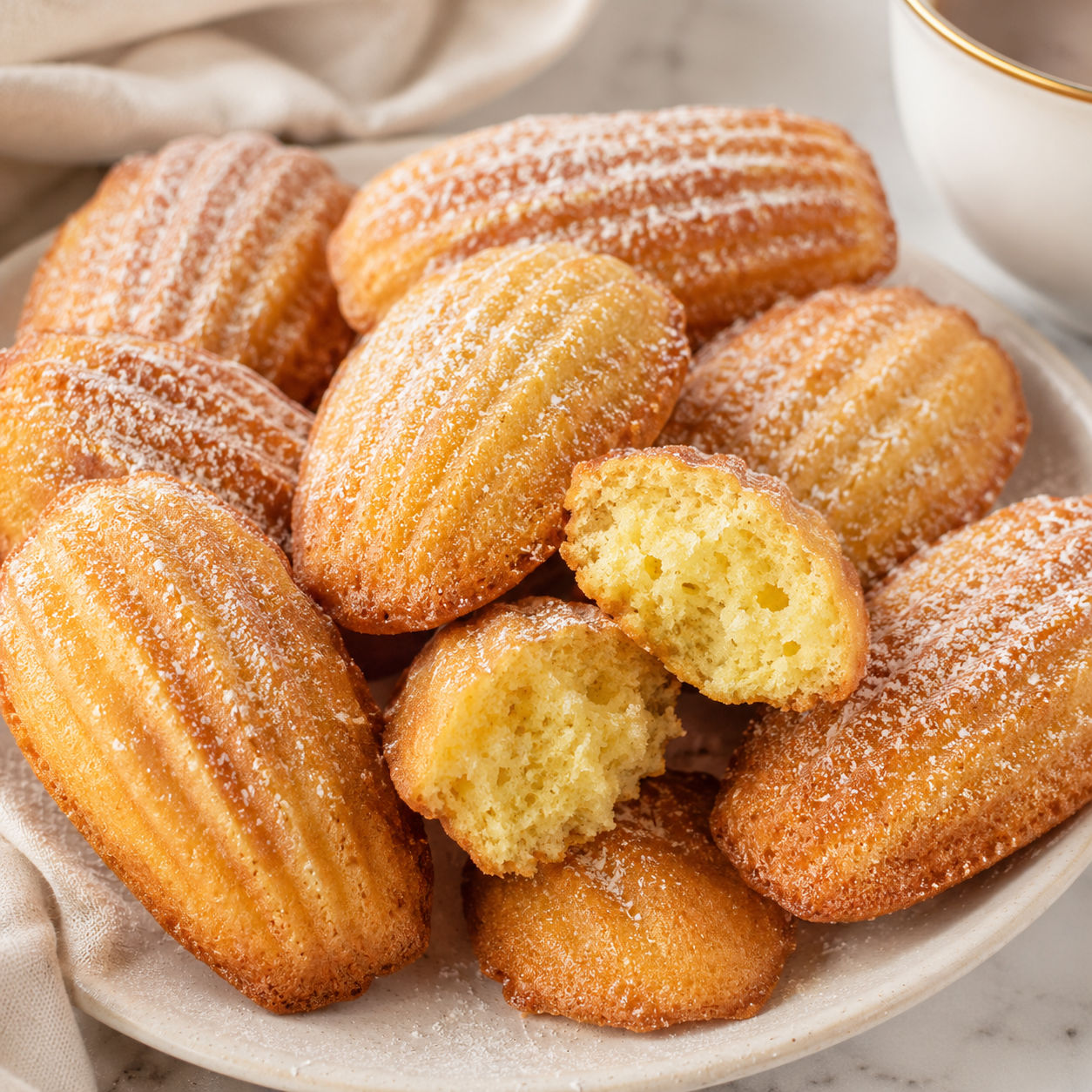 Classic French madeleines with powdered sugar and golden shell ridges