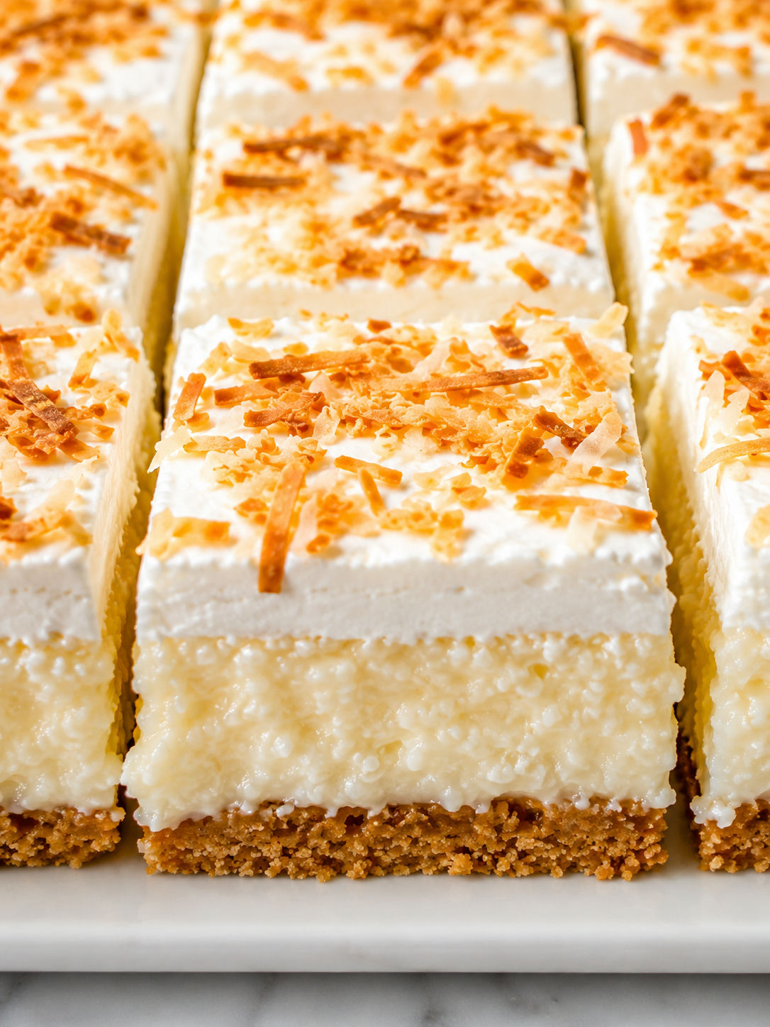 Coconut Cream Bars stacked with toasted coconut and creamy layers