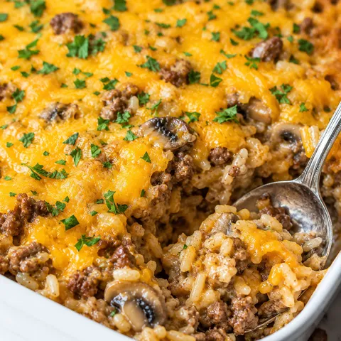Beef and rice casserole with melted cheddar and parsley in a white dish
