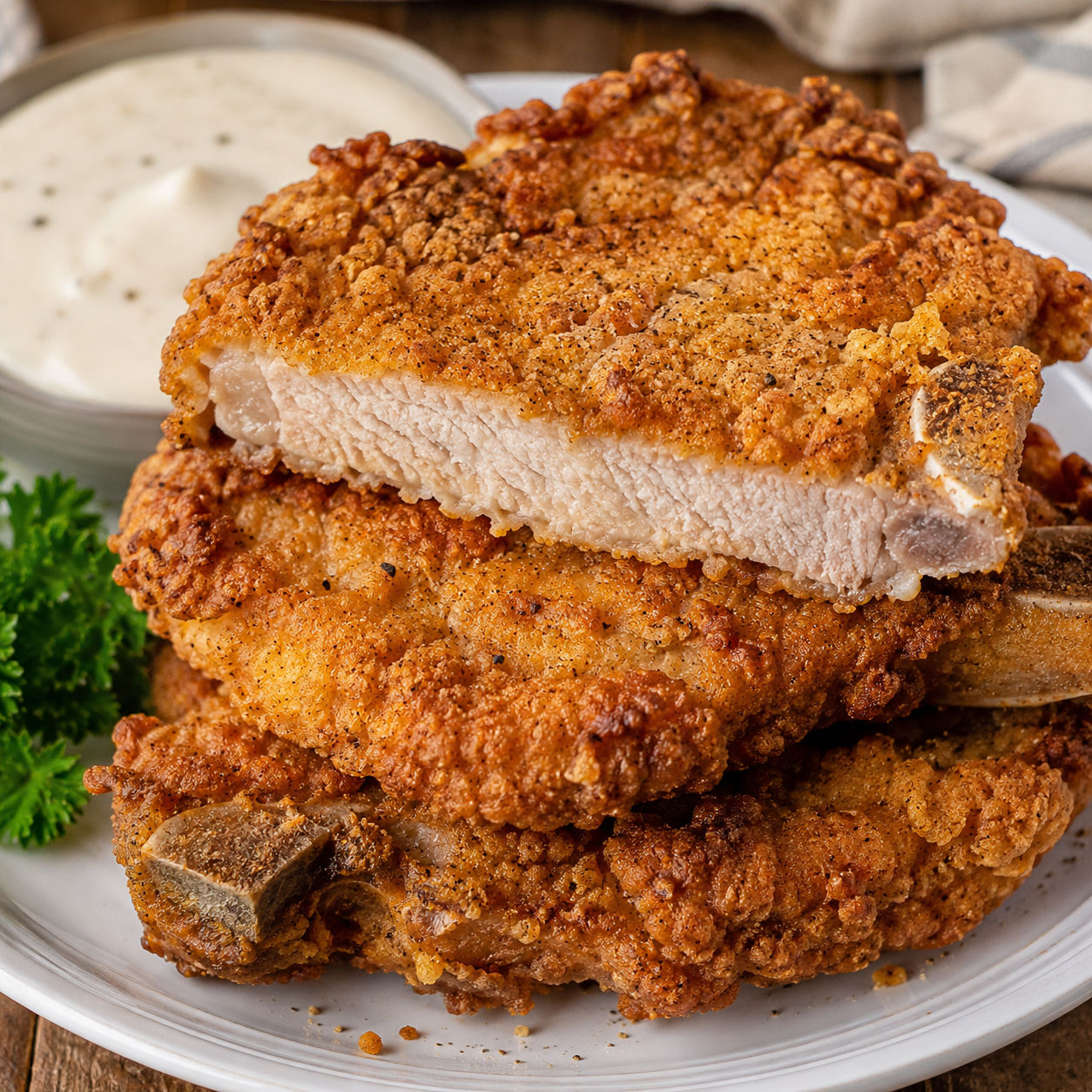 Golden country fried pork chops with crispy seasoned crust on a white plate