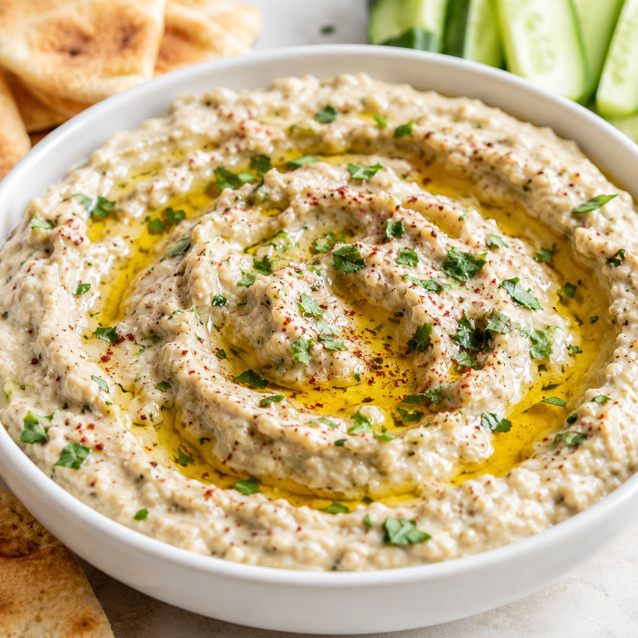 Creamy baba ganoush with olive oil, parsley, sumac, pita, and cucumber