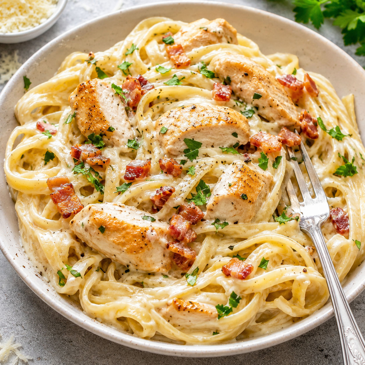 Creamy chicken carbonara with bacon, Parmesan, and parsley in a white bowl