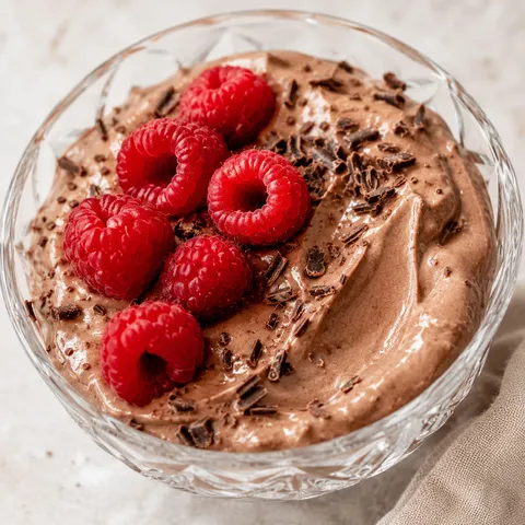 Creamy chocolate protein pudding with raspberries and shaved chocolate