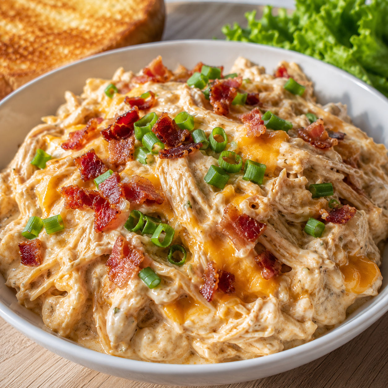 Creamy ranch crack chicken with bacon, cheddar, and green onions in a bowl