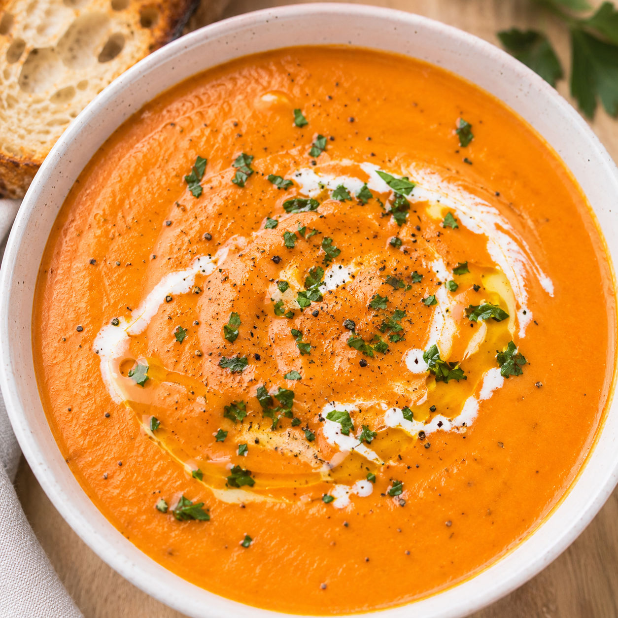 Creamy roasted red pepper potato soup with cream swirl and parsley