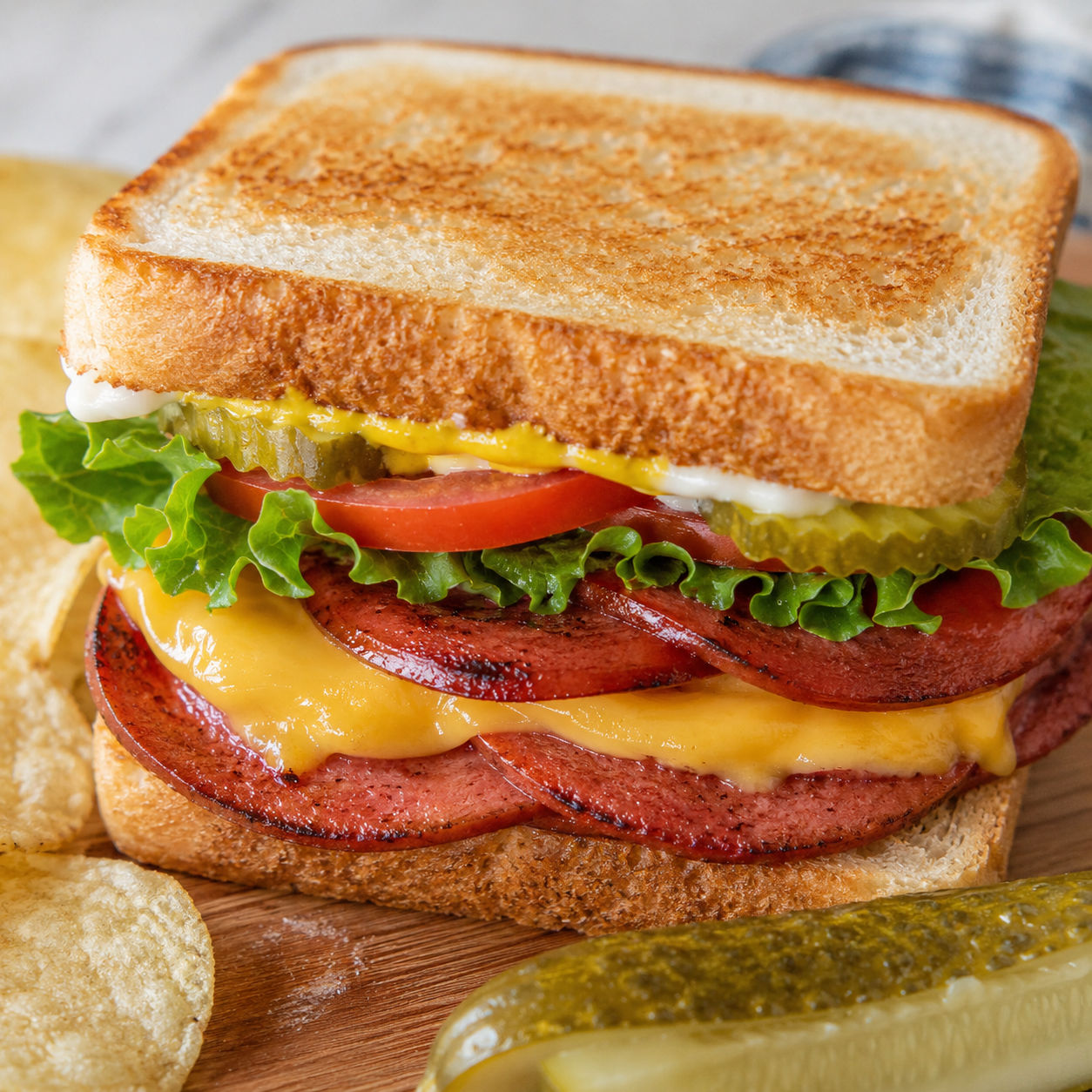 Air-fried bologna sandwich with melted cheese, pickles, lettuce, and tomato