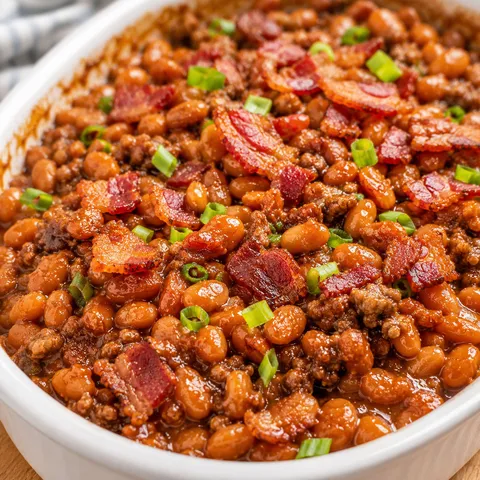 Baked beans with ground beef, crisp bacon, and green onions in a casserole dish