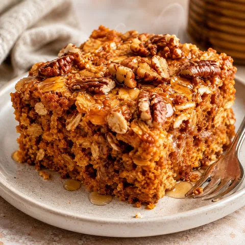 Pumpkin baked oatmeal square with pecans and maple syrup on a plate