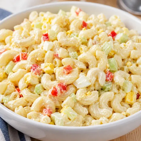 Creamy sweet macaroni salad with eggs and vegetables in a white bowl