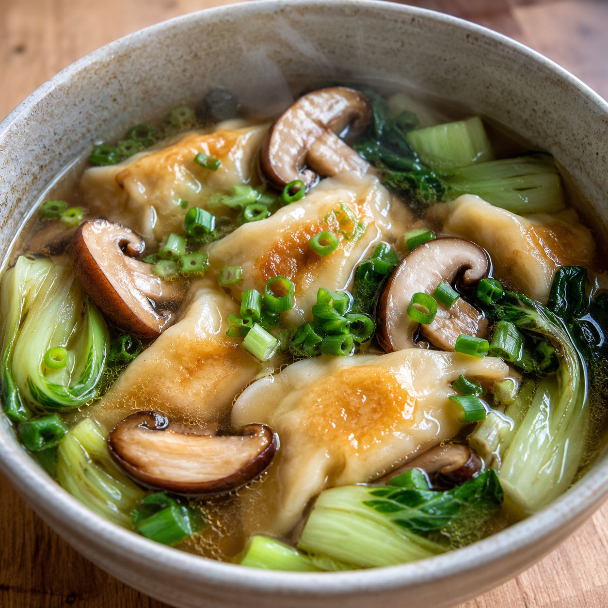 Potsticker soup with mushrooms and bok choy in a ceramic bowl