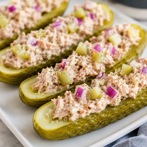 Tuna pickle boats with creamy filling and red onion on a white plate