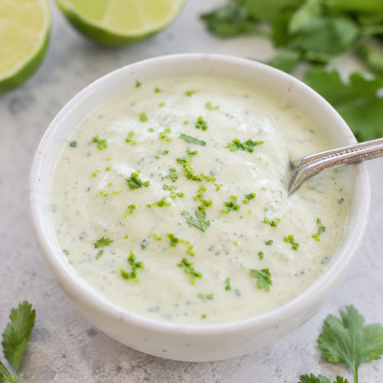 Cilantro lime crema in a white bowl with lime and cilantro