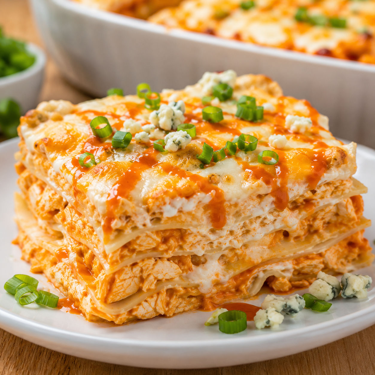 Buffalo ranch chicken lasagna slice with melted cheese and green onions