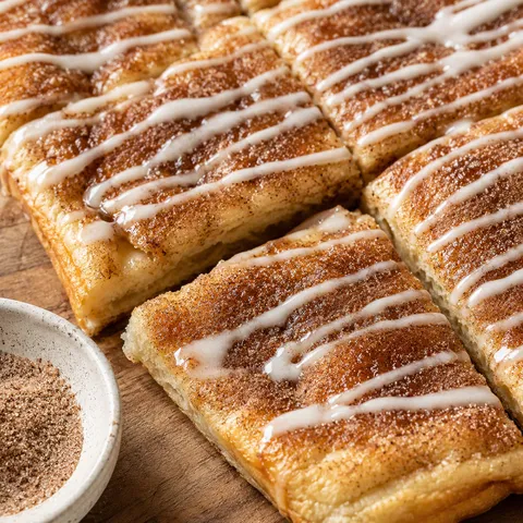 Cinnamon-sugar pizza with vanilla glaze drizzled on top, sliced into squares